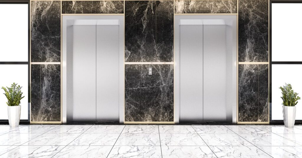 Two closed elevator doors in a marble lobby of a modern building